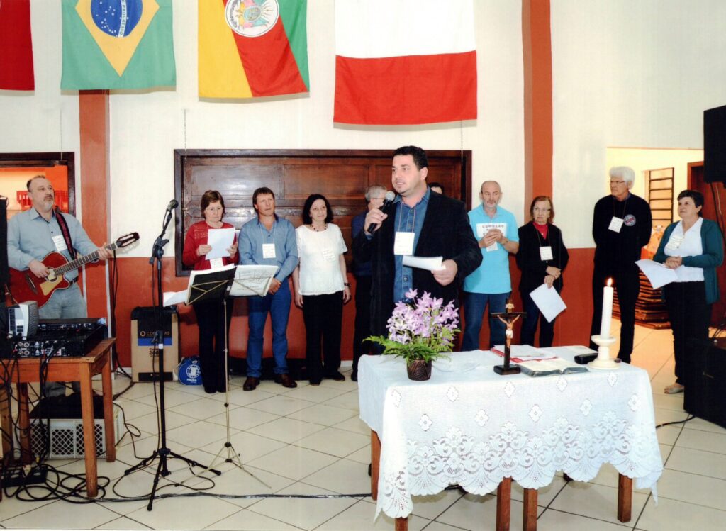 Moisés Dametto, mestre de cerimônia, dá as boas-vindas aos convidados e apresenta breve histórico da Família. Ao fundo: Marizete Natalina Dametto, César Dametto, Nair Dametto, Helio Dametto, Sergio Dametto, Osana Dametto Coronetti, Telmo Dametto e Lourdes Maria Andreolli Dametto.